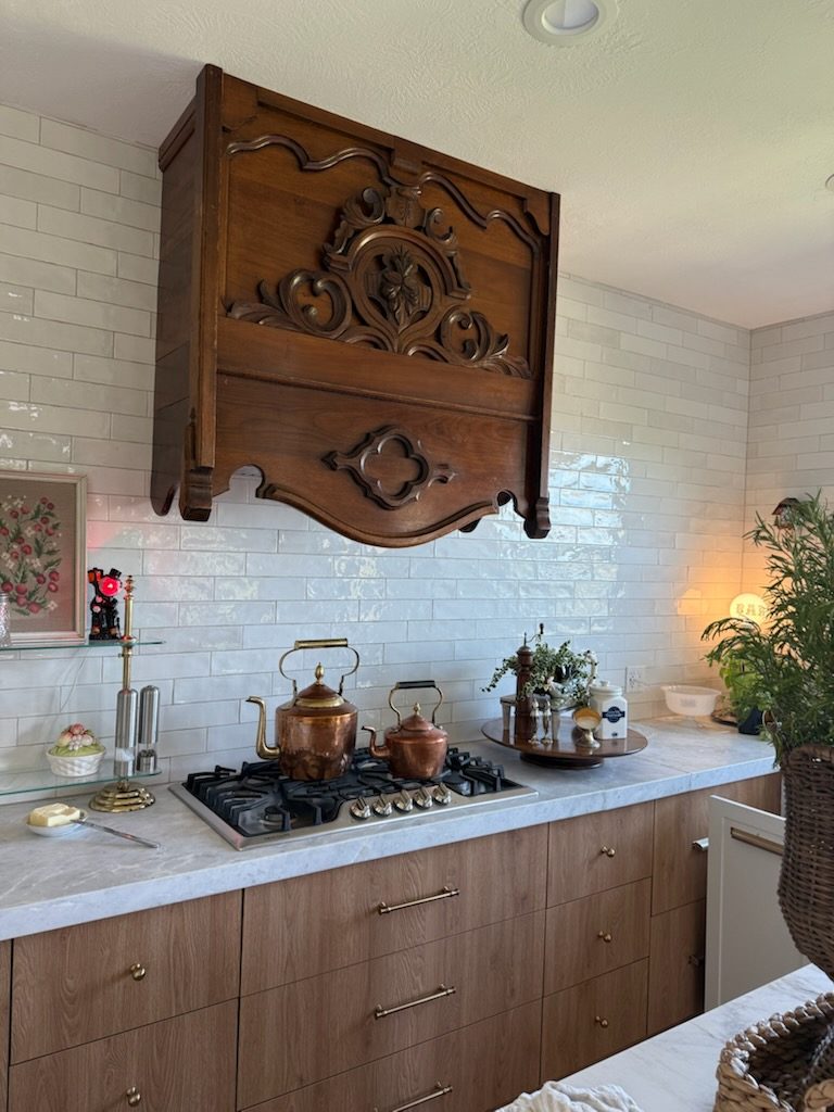 Kitchen remodel with antique carved range hood and marble counters