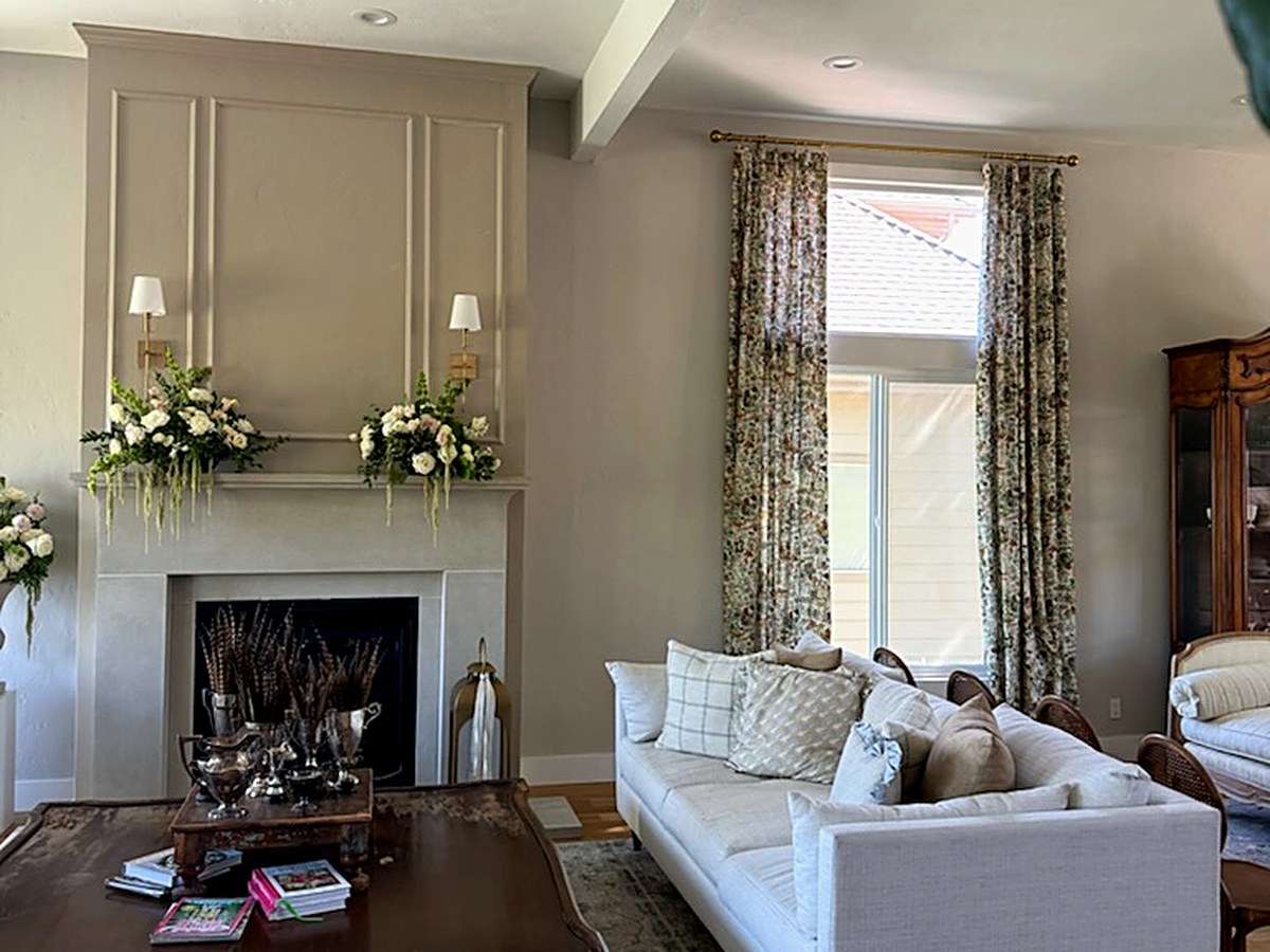 Renovated living room with cast-stone fireplace surround, paneled chimney wall, and ceiling beams